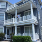 employee painting multi level home exterior blue