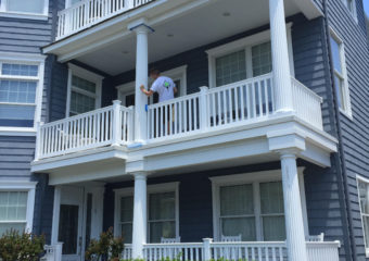 employee painting multi level home exterior blue