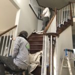 Painters refinishing wooden staircase