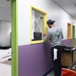 Painting and Wallcovering Employee Taping Trim in School to be Painted